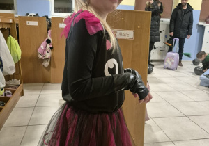 Dziewczynka pozuje do zdjęcia w przedszkolnej szatni. Na sobie ma strój kota.