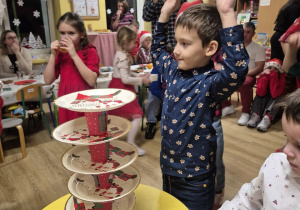 Chłopiec układa wieże ze świątecznych talerzyków i kubeczków.