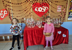 dwie dziewczynki stoją obok stolika z ciasteczkami