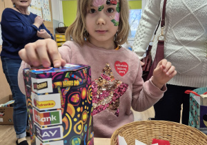 Dziewczynka wrzuca pieniądze do puszki