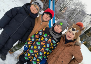 cztereech chłopców ciepło ubranych pozuje do zdjęcia w ogrodzie