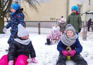 grupa dzieci na górce w przedszkolnym ogrodzie , jedne biegają, inne zjeżdzająna sankach