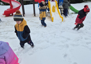 grupa dzieci w przedszkolnym ogrodzie , bawią się na śniegu