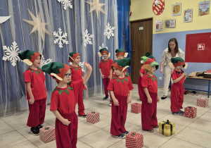 występuje grupa chłopców przebrana za elfy, przed nimi leżą prezenty, które są rekwizytami