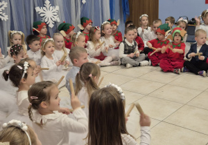 grupa dzieci prezentuje występ świateczny rodzicom, są przebrane za aniołki i elfy , grają na klawesach