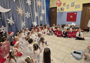 grupa dzieci prezentuje występ świateczny rodzicom, są przebrane za aniołki i elfy , grają na klawesach