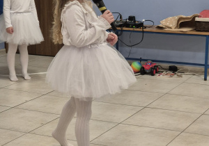 dziewczynka przebrana za śnieżynkę mówi wiersz do mikrofonu