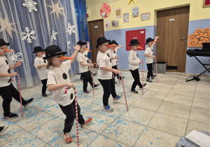 chłopcy przebrani za bałwanki tańczą podczas występu świątecznego, w rękach mają laski