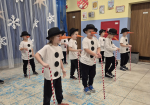 chłopcy przebrani za bałwanki tańczą podczas występu świątecznego, w rękach mają laski