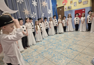 grupa dzieci przebranych za aniołki i bałwanki prezentuje się przed rodzicami na światecznym występie