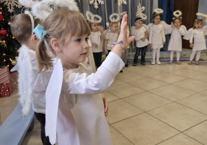 grupa dzieci , niektóre przebrane za aniołki, pozostałe elegancko ubrane prezentuje rodzicom świąteczne przedstawienie