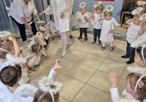 grupa dzieci , niektóre przebrane za aniołki, pozostałe elegancko ubrane prezentuje rodzicom świąteczny taniec