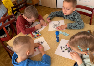 grupa dzieci przy stoliku w bibliotece koloruje obrazki z kwiatami