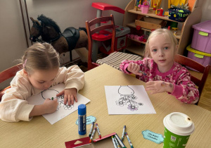 dwoje dzieci przy stoliku w bibliotece koloruje obrazki z kwiatami