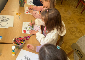 grupa dzieci przy stoliku w bibliotece koloruje obrazki z kwiatami