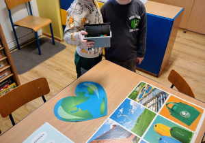 dwóch chłopców stoi przy stoliku na którym leżąplansze edukacyjne