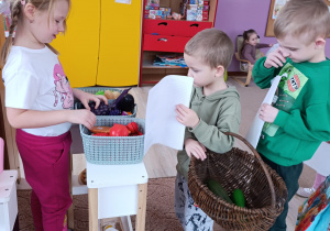 dzieci bawią się w zabawę fabularyzowaną - stojąw kolejce do sklepu, jeden z chłopców ma w ręce koszyk na zakupy