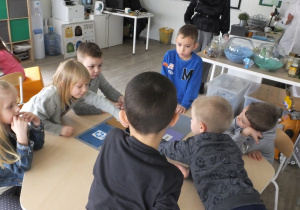 grupa dzieci przy stoliku wykonuje zadanie o tematyce recyklingu