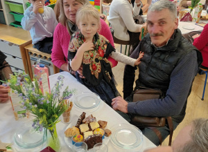 Po części artystycznej, dziadowie z wnuczętami siedzą przy stolikach podczas słodkiego poczęstunku. Celebrują wspólny czas i pozują do zdjęć.