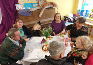 Po części artystycznej, dziadowie z wnuczętami siedzą przy stolikach podczas słodkiego poczęstunku. Celebrują wspólny czas i pozują do zdjęć.