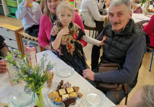 Po części artystycznej, dziadowie z wnuczętami siedzą przy stolikach podczas słodkiego poczęstunku. Celebrują wspólny czas i pozują do zdjęć.