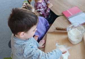 Chłopiec miesza mąkę do przygotowania ciasteczek.