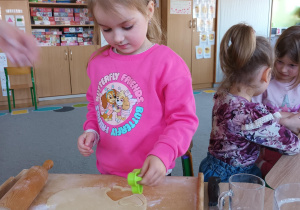 Dziewczynka za pomocą foremek wycina ciasteczka.