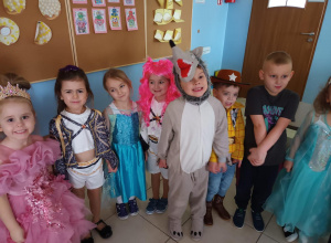 Dzieci pozują do zdjęcia w strojach karnawałowych.