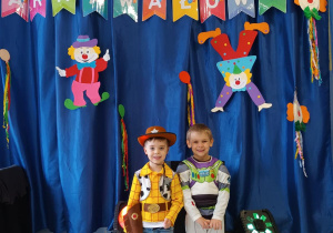 Dzieci pozują do zdjęcia w strojach karnawałowych.