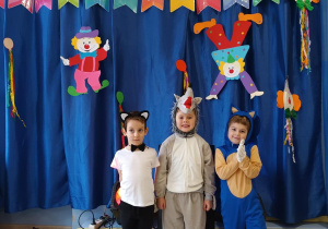 Dzieci pozują do zdjęcia w strojach karnawałowych.