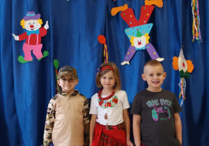 Dzieci pozują do zdjęcia w strojach karnawałowych.