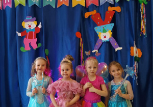 Dzieci pozują do zdjęcia w strojach karnawałowych.