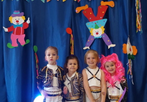 Dzieci pozują do zdjęcia w strojach karnawałowych.