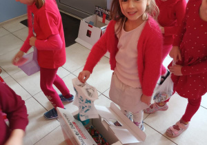 Dziewczynka wrzuca do pudełka zużyte baterie.