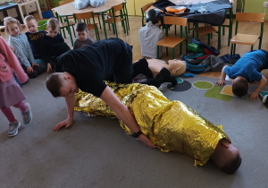 Strażak prezentuje jak prawidłowo wykorzystać koc termiczny.