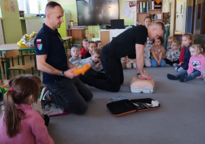 Strażak prezentuje jak wykorzystać defibrylator AED.