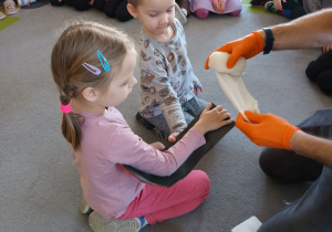 Strażak prezentuje jak zabandażować ranę na ręku dziewczynki.