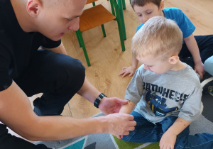 Strażak prezentuje jak oczyścić ranę na ręku chłopca.