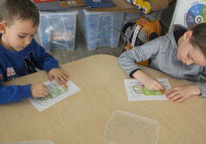 dwóch chłopców koloruje obrazki o tematyce recyklingowej