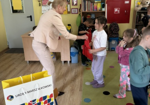 Gościni przekazuje dziewczynce prezent.