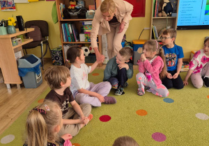 Gościni wita się z dziećmi poprzez podanie ręki.