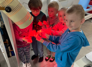Dzieci oświetlone są specjalistyczną lampą do rehabilitacji.