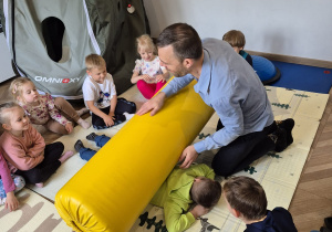 Dzieci ćwiczą z wykorzystaniem wałka rehabilitacyjnego.