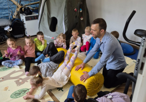 Dzieci ćwiczą z wykorzystaniem wałka rehabilitacyjnego.