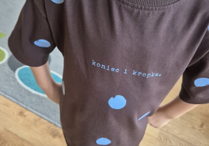 Chłopiec pozuje do zdjęcia, prezentując bluzkę w kropki.