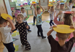 Dzieci unoszą nad głowami kolorowe dyski.