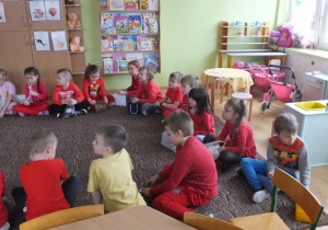 grupa dzieci siedzi na dywanie i słucha