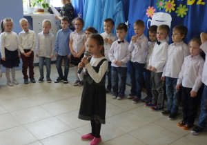 dziewczynka z mikrofonem, w tle grupa dzieci